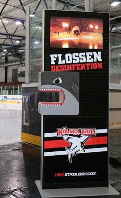 Eine Digital Signage Stele mit Branding der Kölner Haie, mit integriertem Desinfektionsspender.