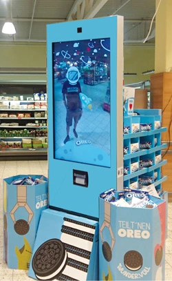 Eine Digital Signage Stele mit zusätzlichen Produktpresentern im Branding einer beliebten Keksmarke. In die Stele ist eine Kamera und ein Fotodrucker integriert.