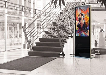 Eine Digital Signage Stele in einem Foyer neben einer Treppe.
